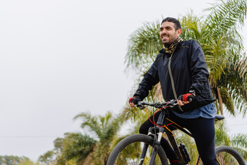 young hispanic latino male athlete on bike smiling looking at the horizon in the morning