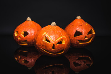 orange and carved pumpkins in row on black, halloween concept
