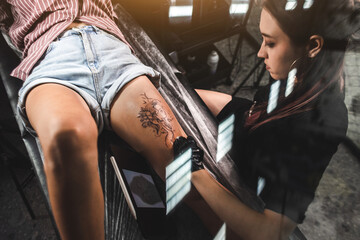Professional female tattoo artist makes a tattoo in the studio, close-up. Dark photography