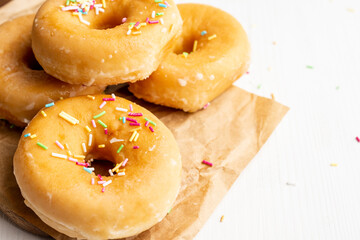 Close-up of several donuts with colored noodles, on brown paper and white table, horizontally, with copy space