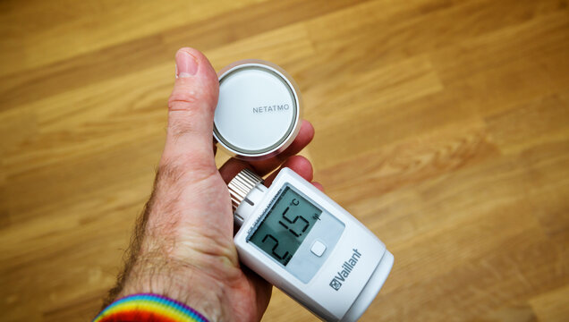 Paris, France - Apr 21, 2020: POV man hand holding two new electronic thermostatic heads - Vaillant Ambisense and Netatmo by Legrand