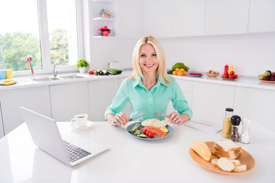 Portrait of smiling good mood stunning mature woman grandmother eat delicious lunch breakfast protein salmon at home kitchen