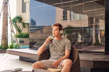 Asian men drinking coffee and listening music by the pool