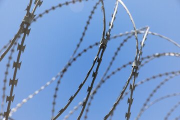 Rusted barbwire and chain link fence. Iron wire on blue sky background on a jail