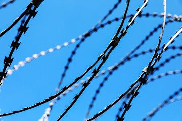 Rusted barbwire and chain link fence. Iron wire on blue sky background