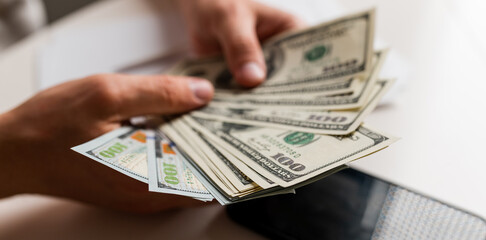 Male hands counting US Dollar bills or paying in cash on money background. Concept of investment,...