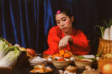 Korean woman in red hanbok has anorexia looking at fresh vegetables and ingredients for making...