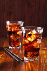 glass of cold cola soft drink with ice on wooden background