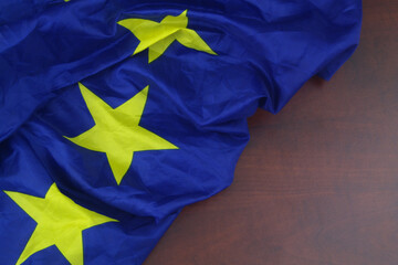 Waved European Union flag on wooden background. Close up of EU flag with copy space for text.