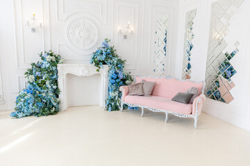 Beautiful luxury classic clean interior living room in white color with pink sofa firepalce flower...