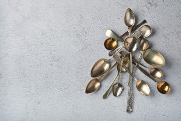 Christmas tree made from old spoons or cutlery with red and green Christmas balls on grey stone or concrete background. Top view with copy space.