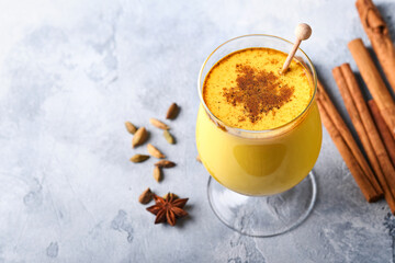 Turmeric golden milk latte with cinnamon sticks and honey. Healthy ayurvedic drink. Trendy Asian natural detox beverage with spices for vegans. Copy space.