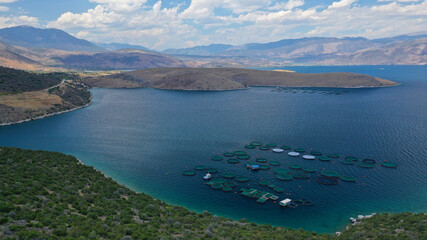Aerial drone photo of large fish farming - breeding unit of sea bass and sea bream in huge round cages with latest technology automatic feeding system, calm deep sea of Anemokambi, Galaxidi, Greece