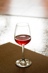 A glass of red wine was placed on the wooden floor.