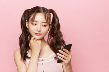 スマートフォンを操作するツインテールの若い女性