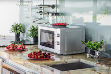 Microwave on counter. Red plates with sweets and berries.