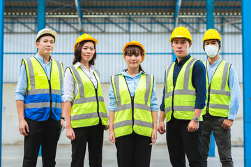 The factory employee consists of engineers, foreman, technicians, and related department staff. Wear a hard hat, and vest. Stand to pose in line looking focus at the camera. Teamwork concept.