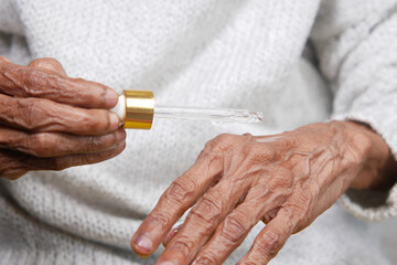 senior women applying essential oils on hand 