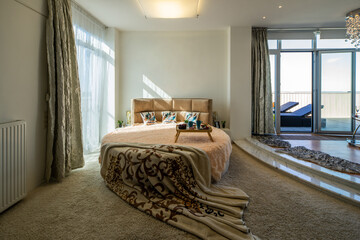 Modern interior of bedroom in luxury apartment. Door to balcony.