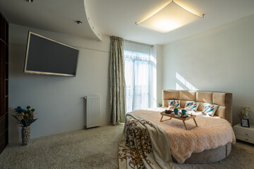 Modern interior of luxury studio apartment. Round bed. TV on wall