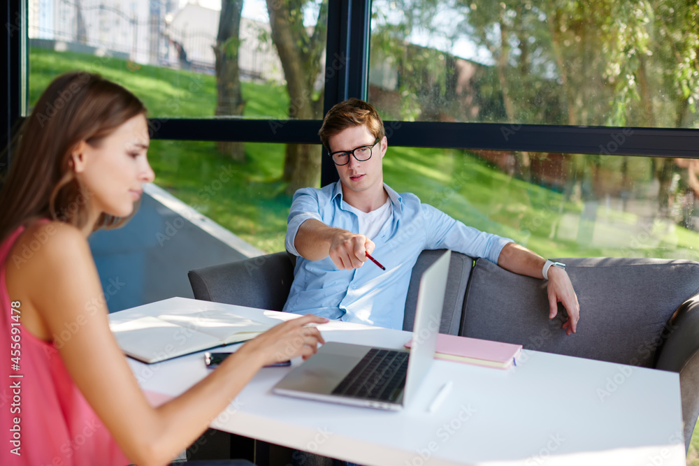 Poster skilled male and female bloggers discussing content plan during together networking on modern laptop