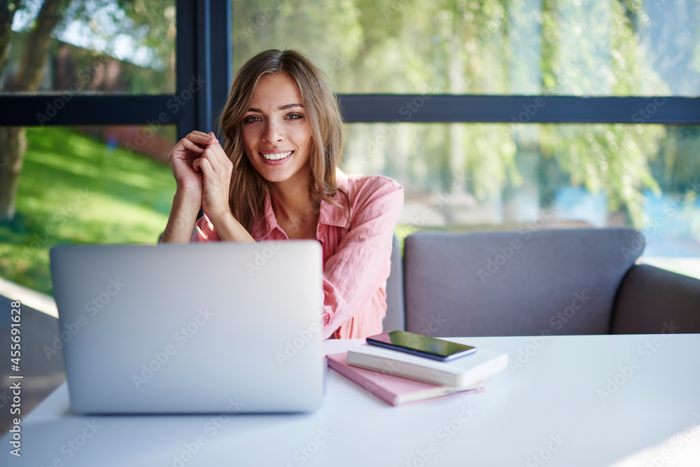 Poster portrait of happy female freelancer using laptop computer for web blogging in coworking space, cheer