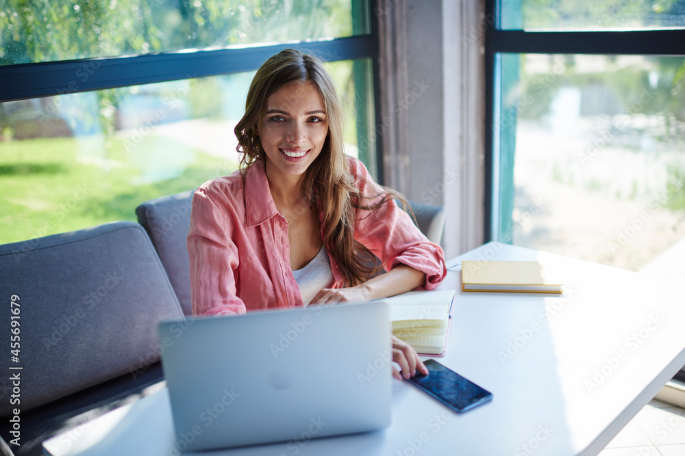 Poster portrait of joyful caucasian generation z using modern laptop and smartphone technology while e lear