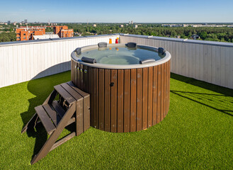 Wooden hot tub on outdoor terrace in luxury apartment. View of city.