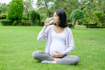 Fototapeta premium Pregnant mother sits drinking clean water in a glass for good health.