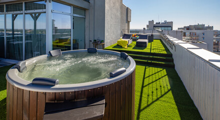 Wooden hot tub on outdoor terrace in luxury apartment. View of city.