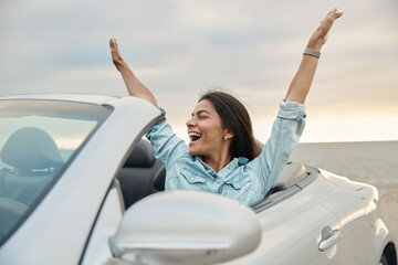 Pleased girl enjoying freedom in cabriolet car - obrazy, fototapety, plakaty