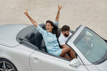 Young european couple riding in cabriolet car