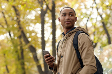 Black male student with cellphone wait for someone