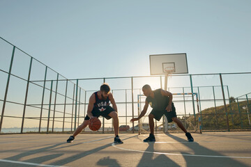 Obraz premium Young sportsmen playing basketball on sports court