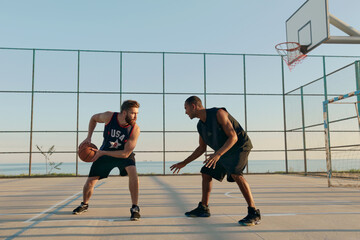 Young sportsmen playing basketball on sports court