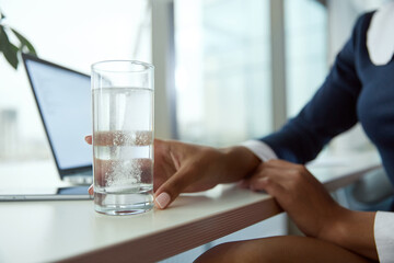 Pill in cup with water in hand of businesswoman