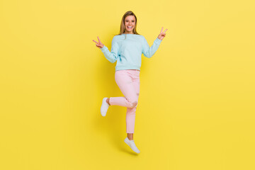 Fototapeta na wymiar Full length body size view of attractive cheerful girl jumping showing v-sign isolated over bright yellow color background