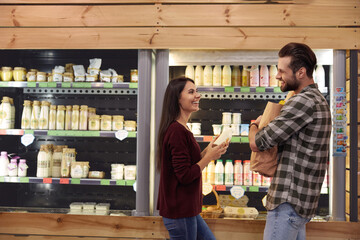 Couple stand and hold groceries in food store