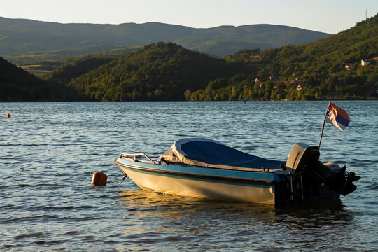 Moror boat on the lake in the late afternoon at sunset behind the hill .  Adobe RGB color space