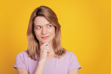 Portrait of cunning playful lady look empty space finger chin clever face on yellow background