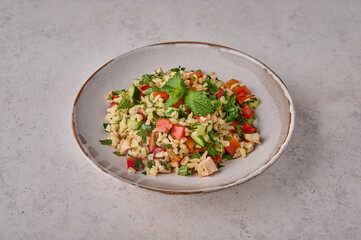 Close up tabbouleh salad. Traditional Middle Eastern or Arabic dish with parsley, mint, bulgur, tomatoes in a bowl on a light background