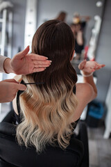 Fototapeta premium stylist hairdresser makes a hairstyle for a girl in his beauty salon, hollywood wave, beautiful hairstyle, hairdresser at work