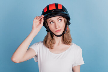 Portrait of interested inspired lady wear motorcycle helmet look blank space on blue background
