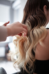 Fototapeta premium stylist hairdresser makes a hairstyle for a girl in his beauty salon, hollywood wave, beautiful hairstyle, hairdresser at work