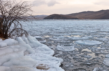 Beautiful unusual winter landscape of Baikal Lake during freeze-up on a frosty December morning. The icy shore of the Olkhon Gate Strait at dawn. Natural background. Changing seasons