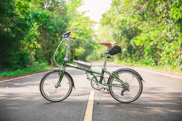 Fototapeta premium Green bicycle on the road. a green bicycle that someone parked in the forest. The bicycle concept of a healthy lifestyle and outdoor activities.