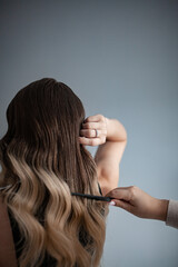 Fototapeta premium stylist hairdresser makes a hairstyle for a girl in his beauty salon, hollywood wave, beautiful hairstyle, hairdresser at work