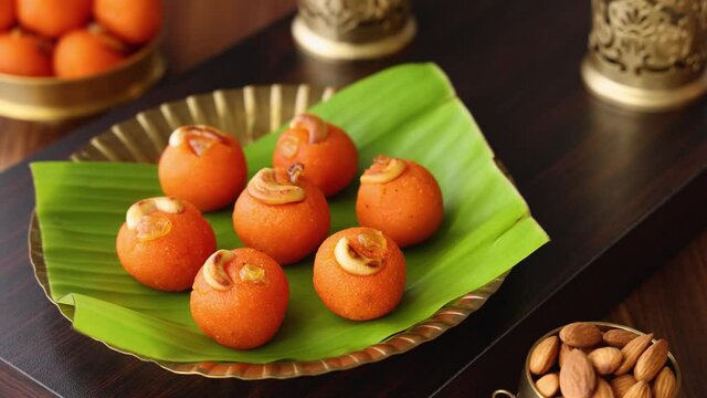 Woman eating Rava Laddu Kesar laddu motichoor Semolina Ladoo Indian sweet mithai 4K footage video Diwali Dussehra Holi Ram Navmi Ganesh chaturthi festival dessert snack golden plate Mumbai India 