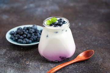 Blueberry yogurt in jar on concrete table background. Healthy food, sweet fitness snack