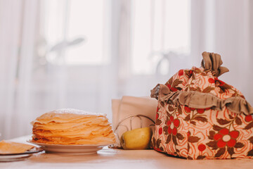 Thin pancakes crepes at kitchen table with cozy details of tableware.